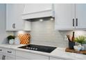 A close-up of the kitchen featuring sleek black cooktop and white cabinets with black hardware at 12051 Lavinia Ln, Charlotte, NC 28277