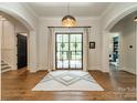 Elegant foyer featuring hardwood floors, a stylish rug, statement lighting, arched doorways and a view of the backyard at 14228 Ryker Way, Davidson, NC 28036