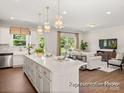 Open concept living space featuring a kitchen island, hardwood floors, and ample natural light at 1509 Autumn Banks Way # 4P, High Shoals, NC 28077
