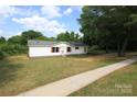 Quaint single-story home featuring white siding, red shutters, and a lengthy concrete driveway at 2002 Kingston Rd, Kingstown, NC 28150