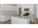 Bright kitchen boasts white cabinets, granite countertops, stainless appliances, and island with sink at 2712 Lehigh Rd, Charlotte, NC 28208