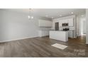 Open-concept living area and kitchen with hardwood floors, white cabinets, stainless appliances, and island at 2712 Lehigh Rd, Charlotte, NC 28208