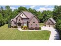 An eye-level view of a beautiful brick home featuring a large manicured lawn and three car garage at 5183 Mill Race Ln, Lancaster, SC 29720