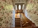 Staircase leading to the front door, features hardwood steps and floral wallpaper at 5495 Valley Run St, Hickory, NC 28601