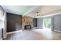 Living room with a striking stone fireplace, neutral walls, fan, new flooring, and sliding glass doors at 8905 Vagabond Rd, Mint Hill, NC 28227