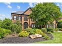 Two-story brick home with a well manicured front yard and large shade tree at 9625 Donna Ve Ln, Charlotte, NC 28277