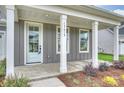 Inviting front porch with white columns, gray siding, and neatly landscaped flower beds at 13618 Tranquil Day Dr, Matthews, NC 28105