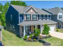 Charming two-story home featuring brick and blue siding, a covered porch, and well-landscaped yard at 17228 River Race Dr, Huntersville, NC 28078