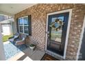 Inviting front porch featuring brick, seating, and a decorative wreath on the stylish black front door at 17228 River Race Dr, Huntersville, NC 28078
