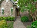 Inviting stone facade with a brick walkway leading to the front door, surrounded by lush landscaping at 1814 Therrell Farms Rd, Waxhaw, NC 28173