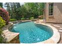 Custom-designed pool with stone accents and a waterfall feature, surrounded by lush landscaping at 18843 Flat Shoals Dr, Cornelius, NC 28031