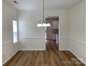 Bright dining room with modern chandelier, chair rail, and light, wood-look floors at 2018 Rockycreek Ln, Monroe, NC 28112