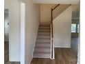 A stairway with carpeted steps and wooden handrail in a well-lit home with light flooring at 2018 Rockycreek Ln, Monroe, NC 28112