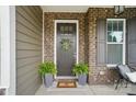 Inviting front door with wreath, ferns, and stylish brick facade creates a warm entrance at 220 Forsythia Ln, Tega Cay, SC 29708