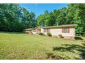 Well-maintained single-story home surrounded by mature trees and a sprawling green lawn, with charming red shutters at 2310 Alexis Lucia Rd, Stanley, NC 28164