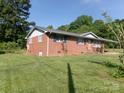 A side view of the brick home showing the lawn, blue shutters, and the landscaping at 2583 Robinson Rd, Newton, NC 28658