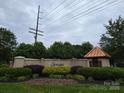 Stonegate entrance featuring lush greenery, mature trees, a stone wall, and charming architecture at 6017 Lowergate Dr, Waxhaw, NC 28173