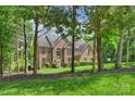 Brick home with mature trees. View of the home through the trees on the front lawn at 706 Evans Manor Dr, Weddington, NC 28104