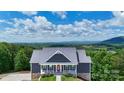 Beautiful aerial view of a blue two-story home with mountain views surrounded by lush green trees at 7768 Pinecone Ln, Hickory, NC 28602
