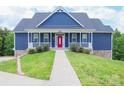 Inviting blue home featuring a covered front porch with white railings and a well-manicured lawn at 7768 Pinecone Ln, Hickory, NC 28602