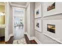 Hallway with wood floors, framed photographs, and an open view into the adjacent dining area at 7908 Rea View Ct, Charlotte, NC 28226
