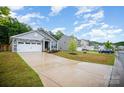Street view of attractive homes featuring well-manicured lawns and driveways under a blue sky with scattered clouds at 107 S Sina St, Troutman, NC 28166