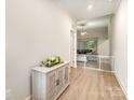 Hallway featuring hardwood floors and a stylish cabinet with floral decorations leading to an open living space at 107 S Sina St, Troutman, NC 28166