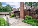Side view of brick home showcasing attached garage, quaint seating area and lush, well-manicured landscaping at 1136 S Edgemont Ave, Gastonia, NC 28054