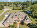 Aerial view of a stately brick home featuring a manicured lawn and mature trees on a sunny day at 150 Northchase Dr, Concord, NC 28027