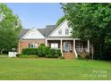 Charming brick home with a manicured lawn, covered porch, and lush green landscaping at 328 Whippoorwill Rd, Mooresville, NC 28117