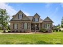 Charming brick and stone two-story home with manicured lawn and inviting front porch at 335 Wintergreen Ct, Kings Mountain, NC 28086