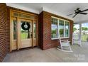 Inviting front porch with rocking chairs, a wood door, and brick accents at 3707 Seagrave Farm Rd, Concord, NC 28025