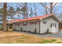 Side view of brick home with a red roof, new landscaping, and private entrance at 4566 Fork Rd, Norwood, NC 28128