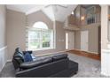 Bright living room with vaulted ceilings, a large window, and a comfortable black sofa at 9315 Pebble Creek Way, Charlotte, NC 28269