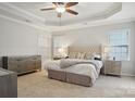 A serene main bedroom featuring a tray ceiling, plush carpeting, and ample natural light at 10401 Royal Winchester Dr, Charlotte, NC 28277