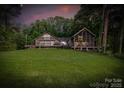Lush lawn and exterior view of lake house featuring two-story structure with screened porch at 230 Shady Cove Rd, Troutman, NC 28166