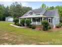 Home featuring a covered porch and a separate outbuilding on a spacious green lawn at 230 Shag Bark Ln, Salisbury, NC 28146
