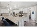 Modern kitchen boasts a large granite island, stainless steel appliances, and stylish pendant lighting at 3218 Gilroy Dr, Fort Mill, SC 29707