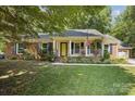 Charming brick home featuring an inviting front porch with a yellow door and blue shutters at 405 Scarborough Ln, Matthews, NC 28105