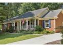 Charming brick home featuring an inviting front porch, well-manicured landscaping, and blue shutters at 405 Scarborough Ln, Matthews, NC 28105
