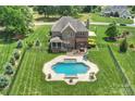 Aerial view of a backyard with a pool, patio area, lush landscaping, and a well-maintained lawn at 4941 Campobello Dr, Monroe, NC 28110