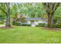 Charming one-story home with mature trees, a lush green lawn, and stylish light blue shutters at 5162 Lincrest Pl, Charlotte, NC 28211