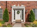 Close up of a white front door with sidelights, a wreath, and manicured landscaping at 611 Meadow Lake Dr, Matthews, NC 28105