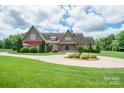 Beautiful home featuring manicured lawn, circular drive, mature trees, and attached garage at 8825 Harris Rd, Concord, NC 28027