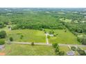 Scenic aerial shot of a sprawling property featuring a mix of verdant meadows, mature trees, and scattered residential houses at 9161 Paul Payne Store Rd, Stony Point, NC 28678