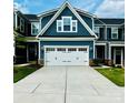 Inviting blue townhome features a white garage door, stone accents, and manicured lawn at 934 Prince Garrett Way, Denver, NC 28037