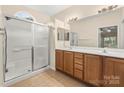 Well-lit bathroom with double sink vanity, tile floors, and glass shower doors at 9430 Duckhorn Dr, Charlotte, NC 28277