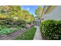 Landscaped backyard featuring a well-manicured lawn, mature trees, and a cozy screened-in porch at 10338 Hollybrook Dr, Charlotte, NC 28277