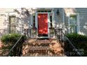 Inviting front entrance with brick steps, black railings, a vibrant red door and decorative plants at 10338 Hollybrook Dr, Charlotte, NC 28277