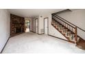 Spacious living room with a brick fireplace, staircase, and neutral carpet, creating a cozy atmosphere at 1330 5Th Ne St, Hickory, NC 28601
